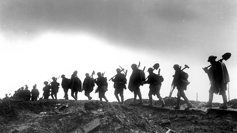 Black and white photograph, soldiers in silhouette marching away from camera, carrying tools. World War I (Limerick Archives)