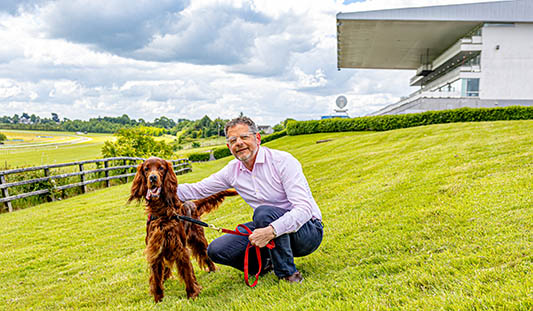 Mayor of Limerick, John Moran crouching on grass next to his red setter dog 