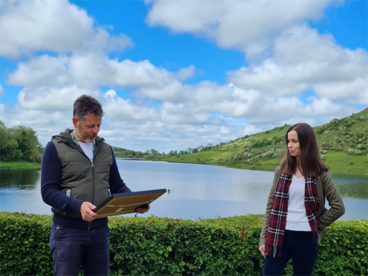 Mayor of Limerick John Moran holding a frame standing in front of Lough Gur
