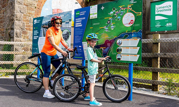 Grandmother with grandson on bikes looking at signage at Abbeyfeale section of Limerick Greenway