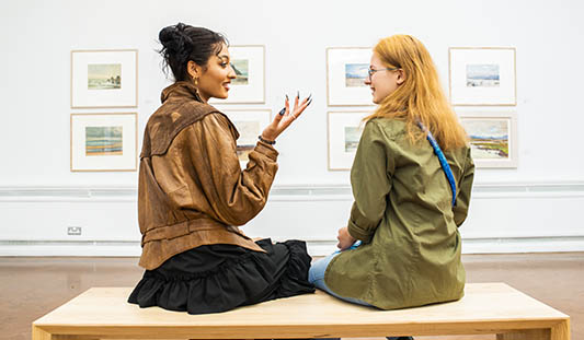 Two women sitting on a bench talking to each other an exhibition at Limerick City Gallery of Art