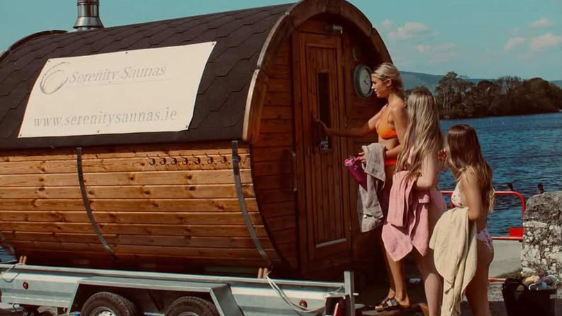Three women using mobile sauna by the lake