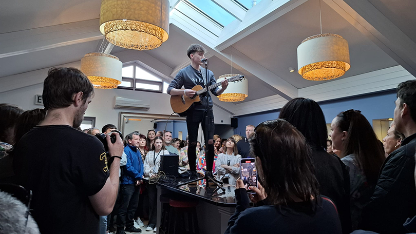 Artist surrounded by crowds singing and playing guitar