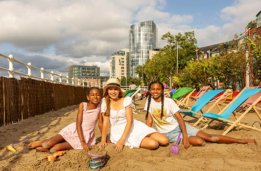 Three girls enjoying the urban beach at Steamboat Quay as part of Summer in the City in Limerick. Photo: Kieran Ryan Benson