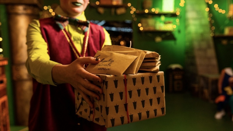 A Christmas Elf presenting festively wrapped presents and a letter to Santa Claus