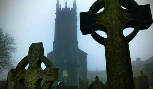 Two dark grave headstones against the foggy backdrop of St. Mary's Cathedral